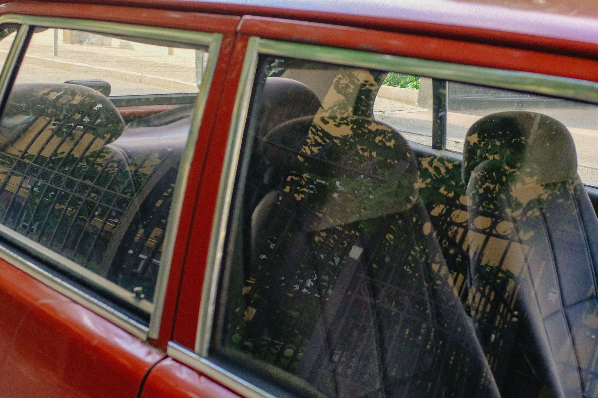 Interior of a vintage car with reflections of trees on the glass windows.